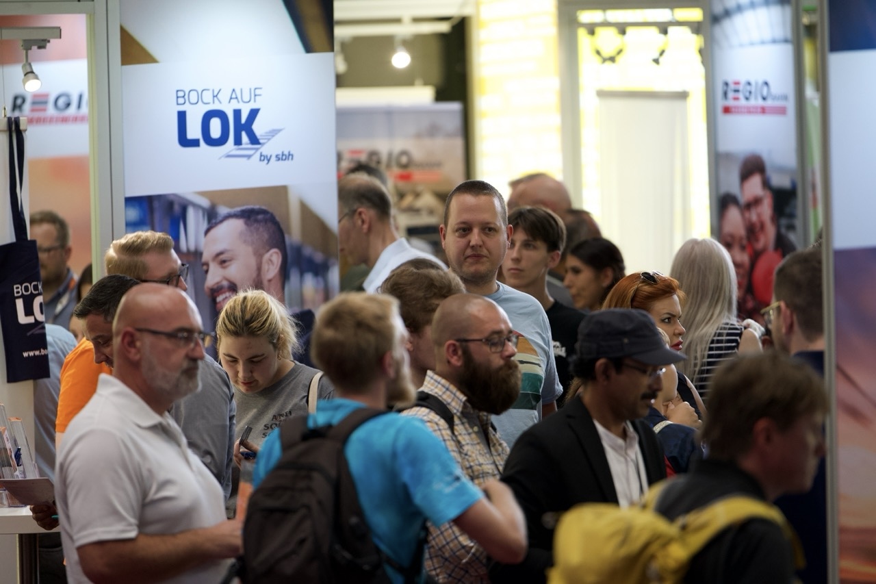 Viele Menschen stehen gedrängt in einem Raum. Im Hintergrund ist ein "Lok"-Plakat.