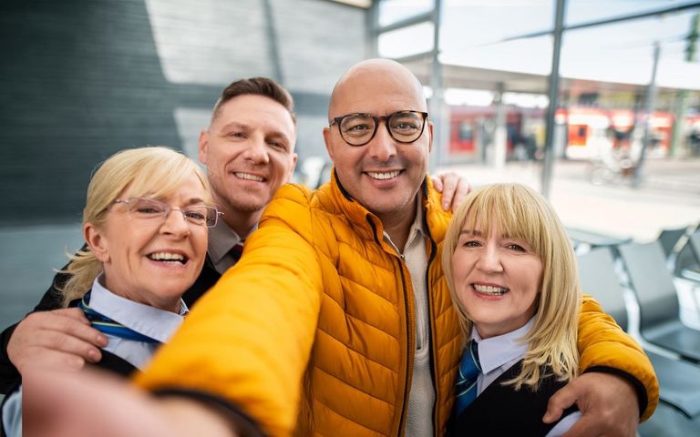 Eine Gruppe von Bahner*innen posiert für die Kamera an einem Bahnhof